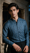 A man wearing a bottle green long-sleeve button-up shirt with a subtle grid pattern of small cross stitch. 