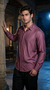A man wearing a long-sleeve button-up shirt in a dusty plum purple color with decorative vertical embroidery on the chest, paired with black trousers, posing in front of a stone archway at night.