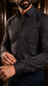 A man wearing a black silk long-sleeve button-down shirt with subtle stingray embroidery on the right sleeve.
