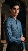 A man wearing a bottle green long-sleeve button-up silk shirt with a subtle grid pattern of small cross stitch. party wear
